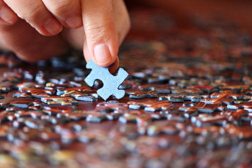 Fingers placing jigsaw puzzle pieces